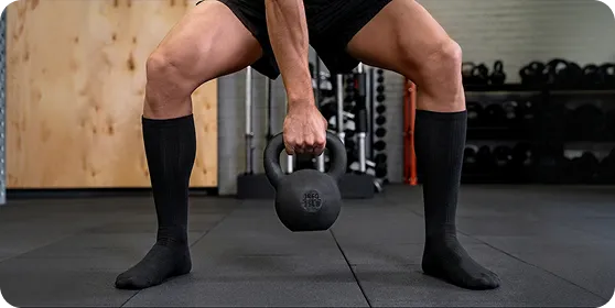 Man performing a kettlebell deadlift in black high-performance socks by Ion Sportswear