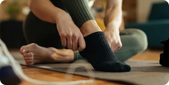 Ion Sportswear black ankle socks on an athlete sitting on a yoga mat